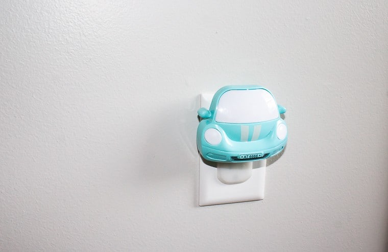 A light blue car nightlight plugged into to an outlet
