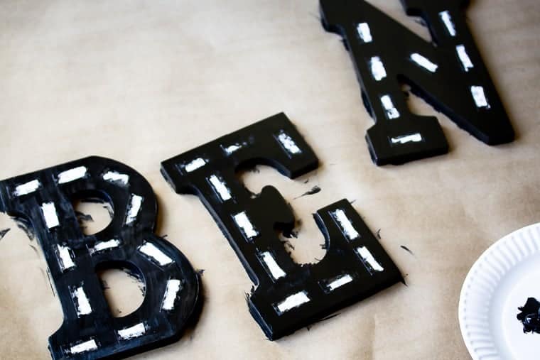 Wood letters B, E, and N painted black with white stripes to look like a road