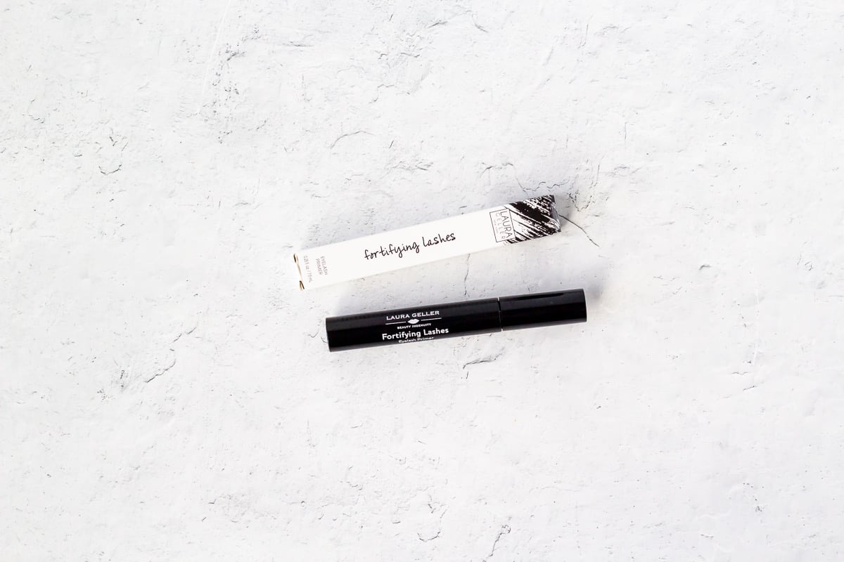 Laura Geller Fortifying Lashes Eyelash Primer on a white background next to it's packaging