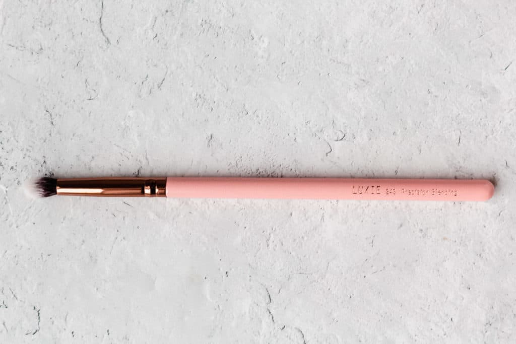 A pink Luxie eyeshadow brush on a white background