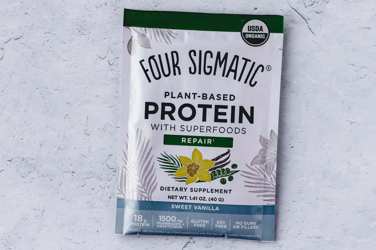 A packet of Four Sigmatic Plant-Based Protein Sweet Vanilla on a gray background