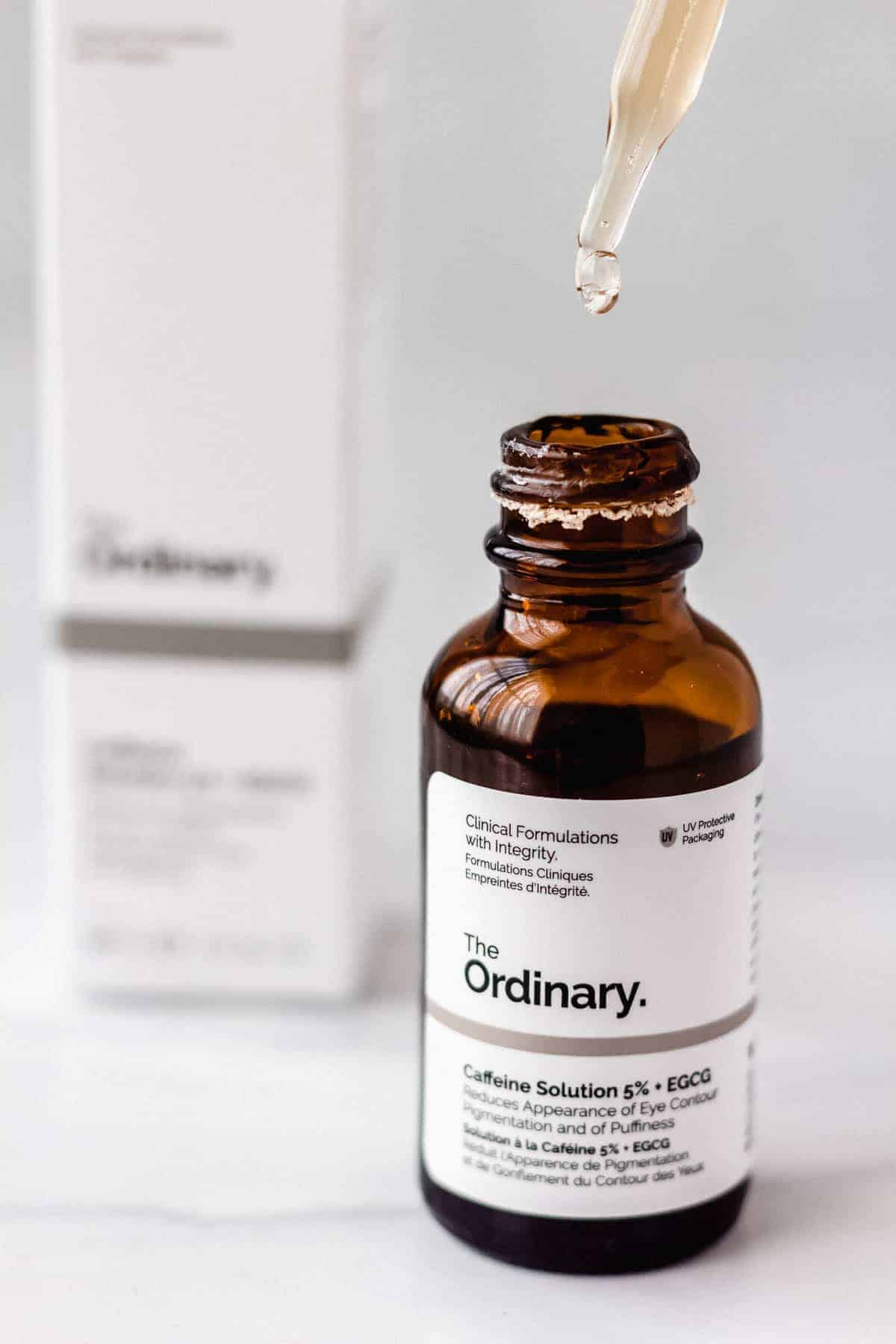 The Ordinary Caffeine Solution with the dropper being lifted out with a drip coming off of it