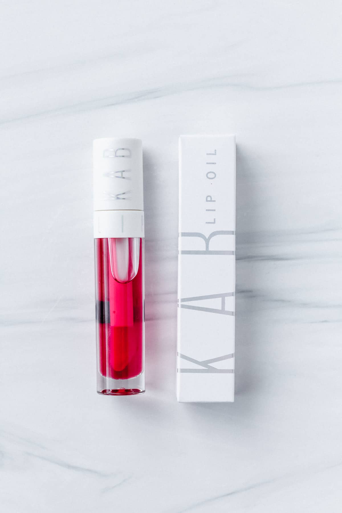KAB cosmetics lip oil in rum punch bottle and box on a white background