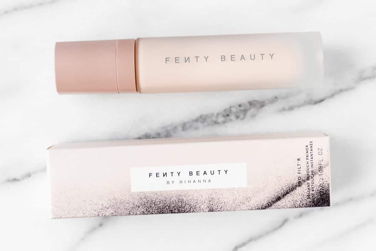 Fenty Beauty Pro Filt'r Instant Retouch Primer bottle and box on a marble background