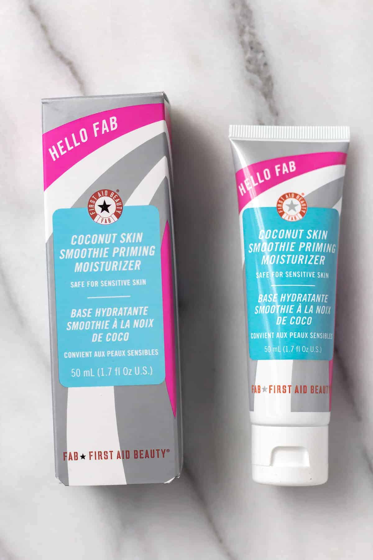 First Aid Beauty Hello Fab Coconut Skin Smoothing Priming Moisturizer and box on a marble background