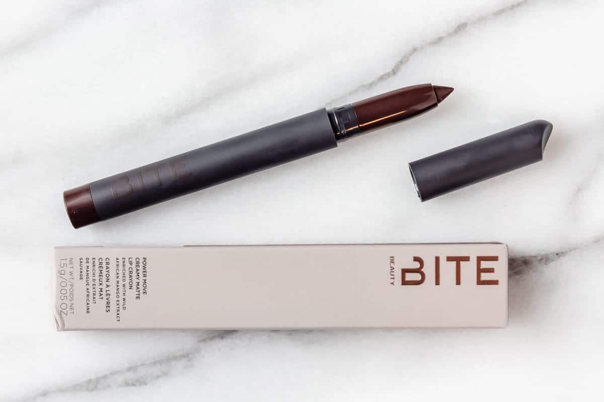 Bite Beauty Power Move Creamy Matte Lip Crayon in Cognac opened on a white marble backdrop