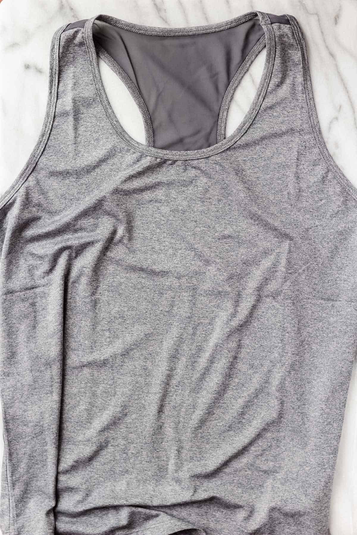 Jessica Simpson Excel Active Tank in Heather Ombre Blue on a marble background