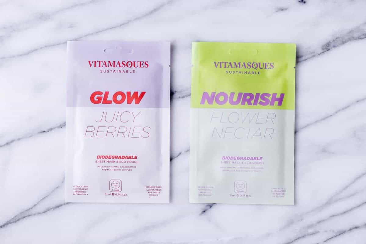Vitamasques Nourish Flower Nectar Biodegradable Mask and Glow Juicy Berries Biodegradable Mask packets on a marble background