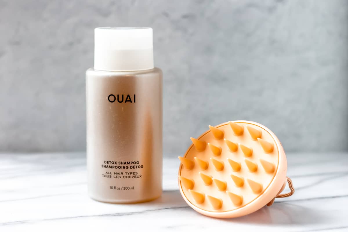 OUAI Detox Shampoo + Scalp Massager on a gray background