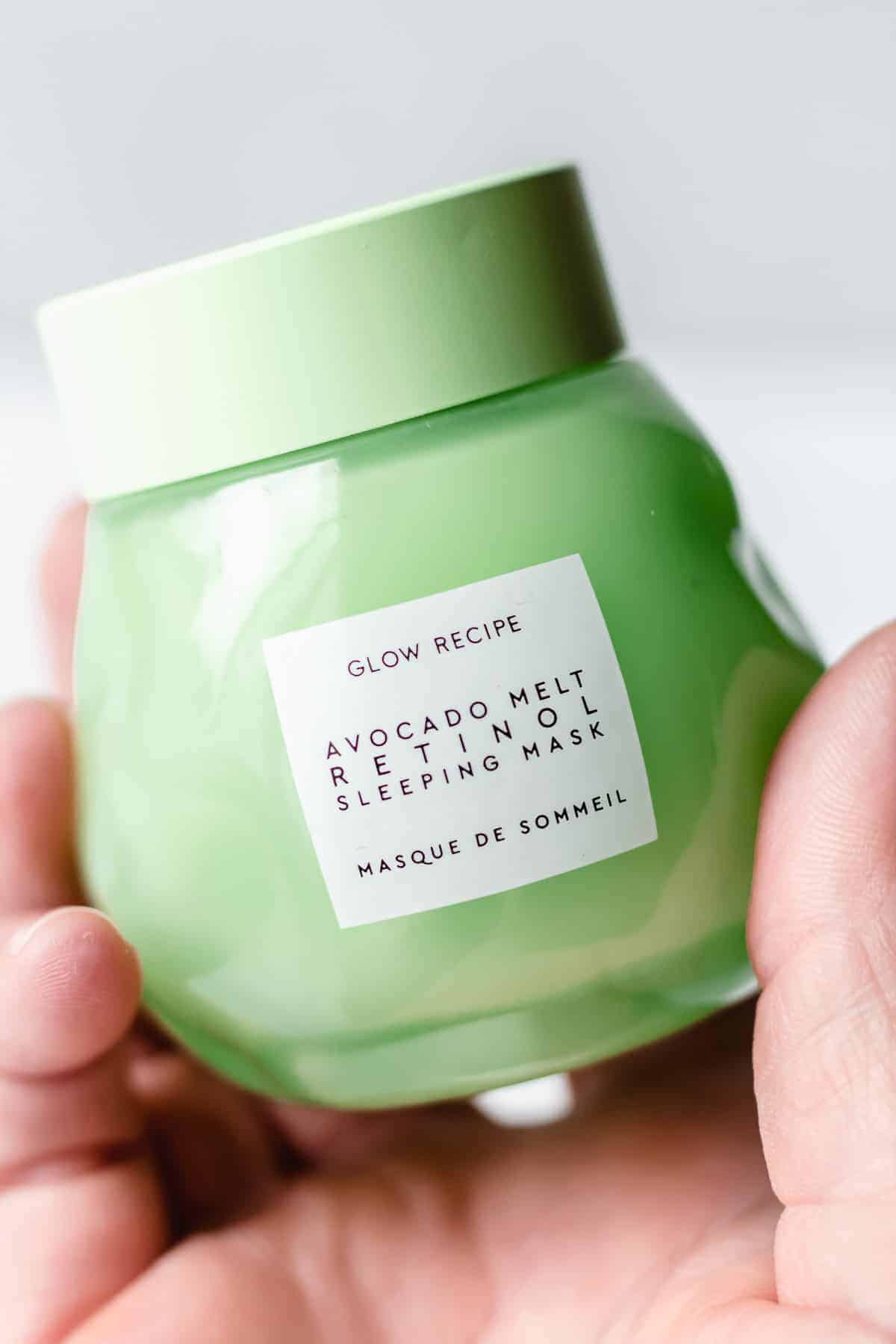 Close up of a hand holding jar of glow recipe avocado melt retinol sleeping mask
