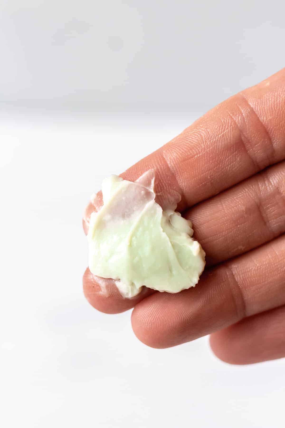 Light green facial cream on fingertips