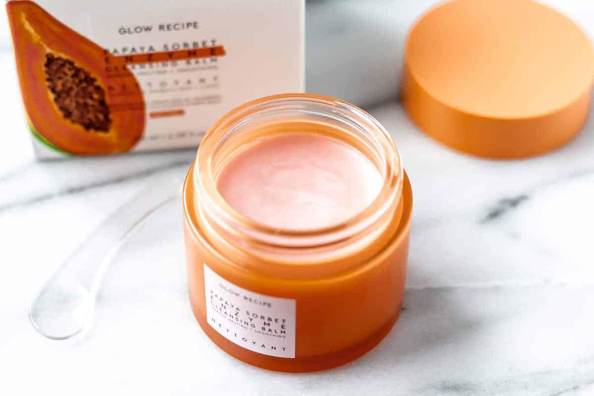 An opened jar of papaya sorbet enzyme cleansing balm with the lid, box and spatula around it