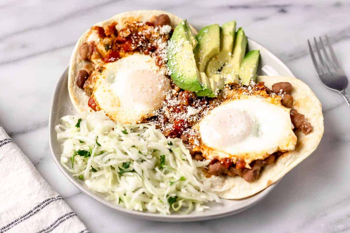 Huevos Rancheros with Refried Beans, Salsa & Avocado from Gobble on a white plate