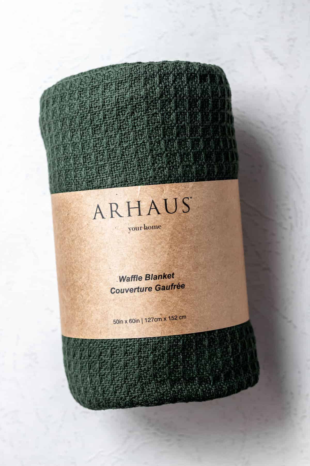 Arhaus Waffle Knit 100% Cotton Throw Blanket in green rolled up in it's packaging