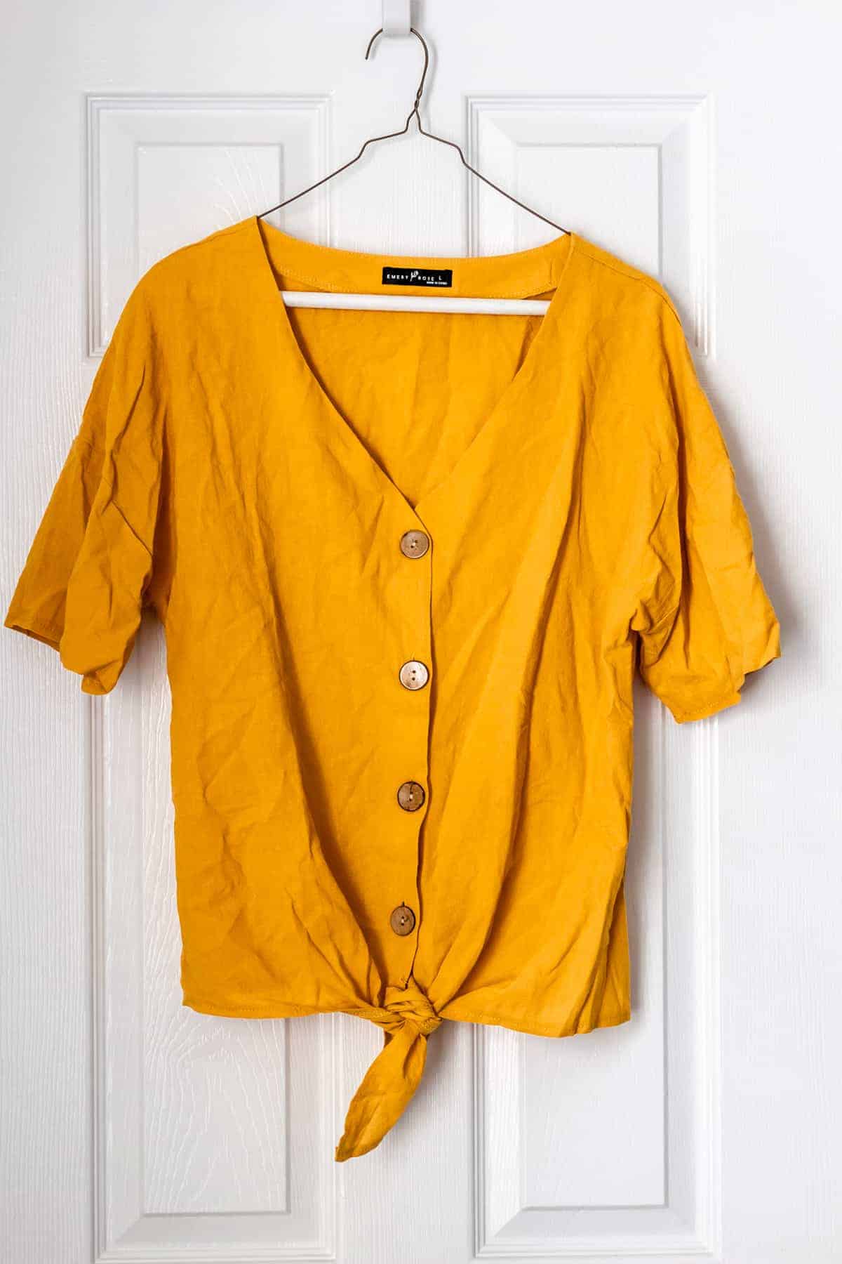 EMERY ROSE Solid Button Front Knot Hem Blouse in yellow on a hanger