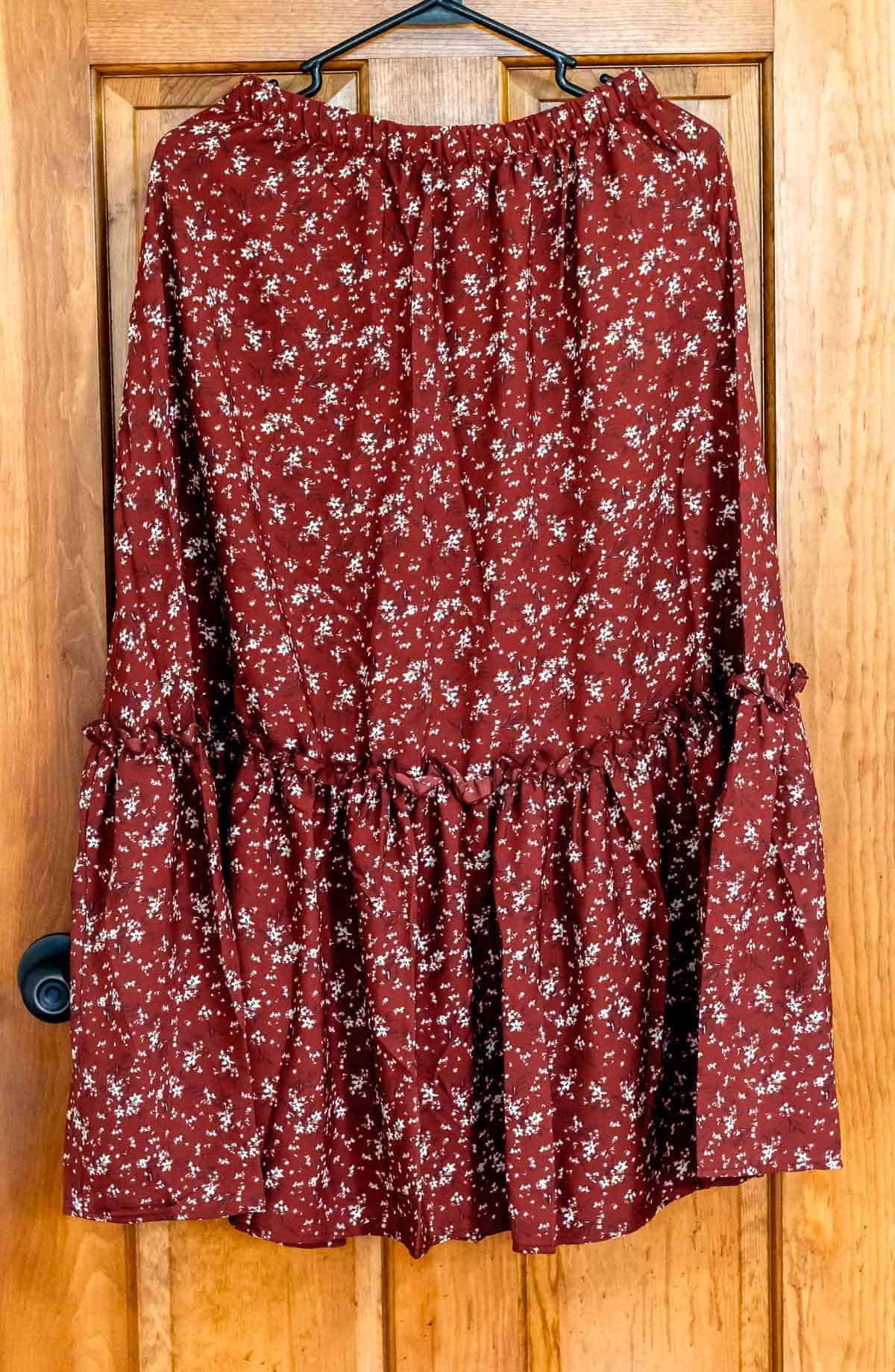 Red Ditsy Floral Frill A-line Skirt on a hanger in front of a wood door