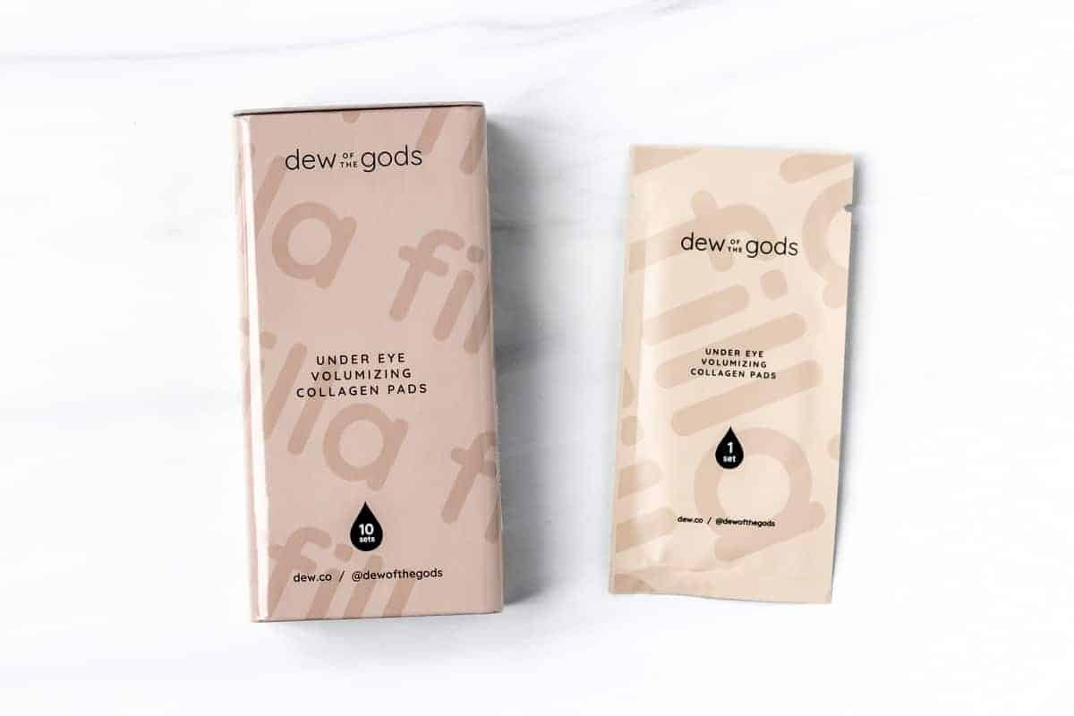 Dew Of The Gods Under Eye Volumizing Collagen Pads box and single packet on a white background.