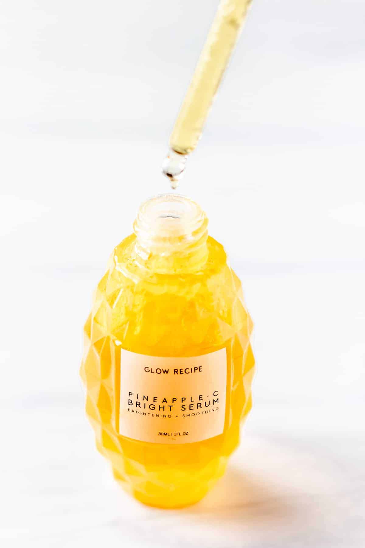 A dropped full of Glow Recipe Pineapple-C Bright Serum being held over the bottle.