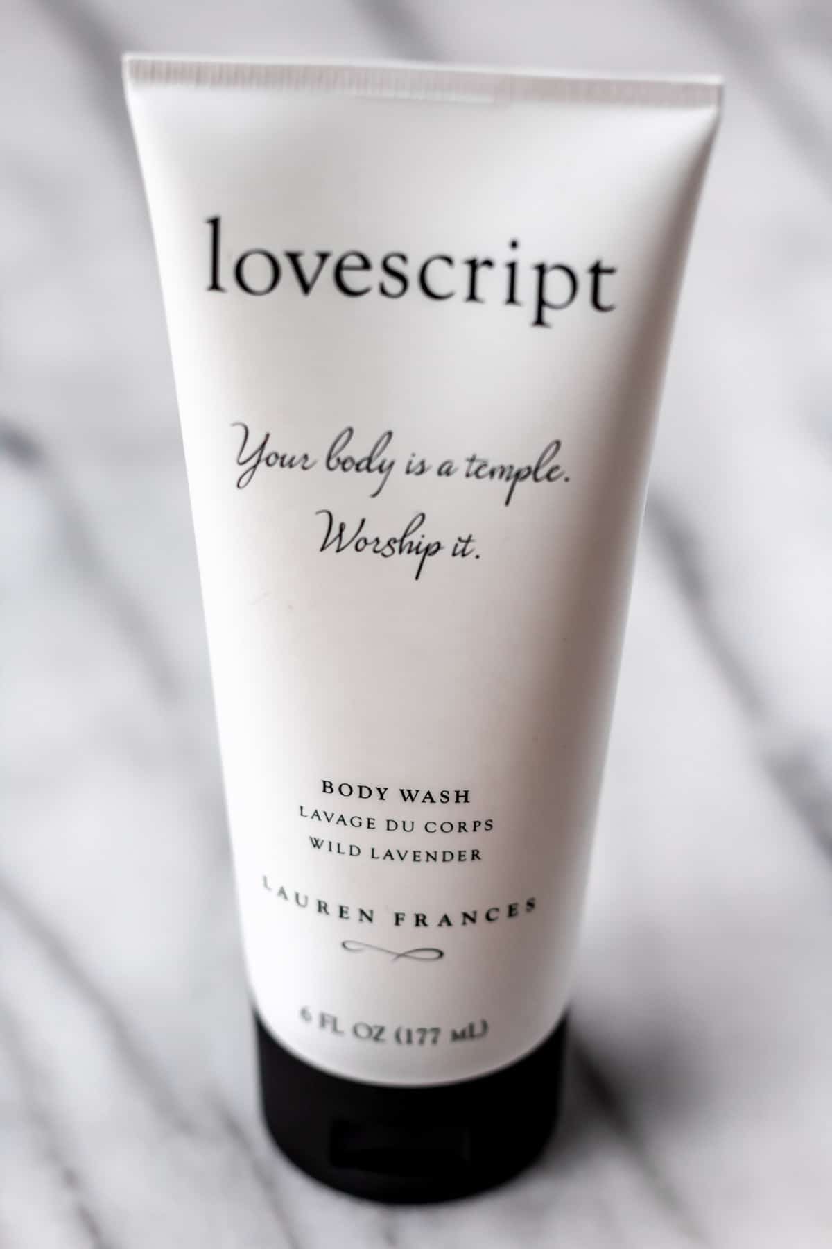 Lovescript body wash tube on a marble background.
