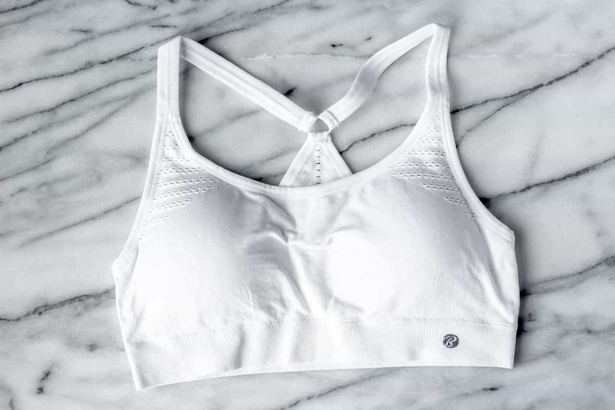 Bally Total Fitness Kira Sports Bra in white on a marble background.
