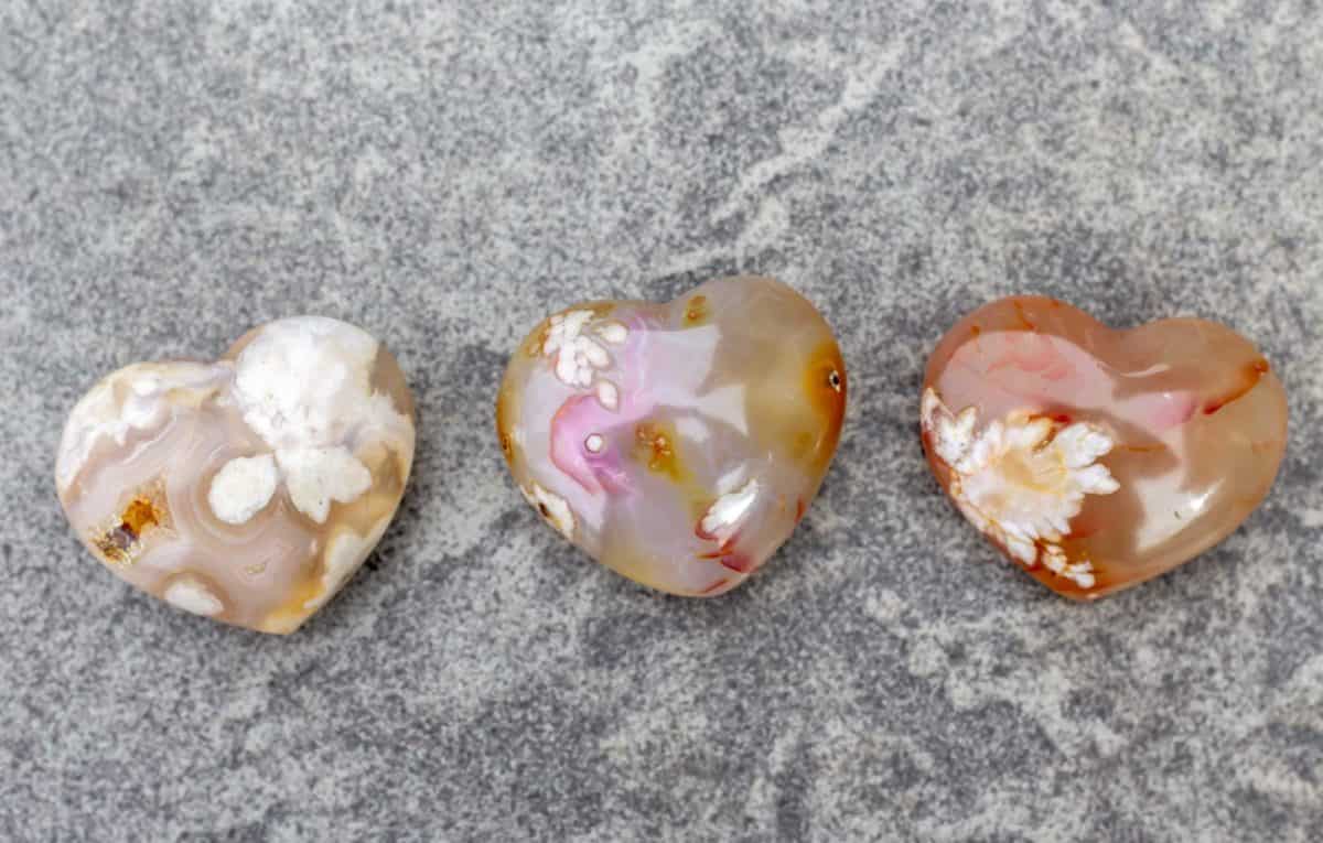 Three flower agate hearts on a gray table background.