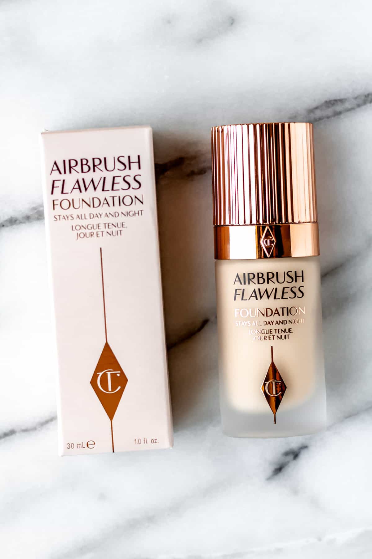 Charlotte Tilbury Airbrush Flawless Foundation packaging and bottle on a marble background.