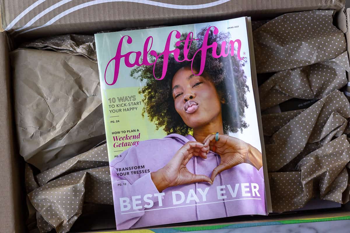 An opened Spring 2022 FabFitFun box with the magazine on top of paper covering the items inside.
