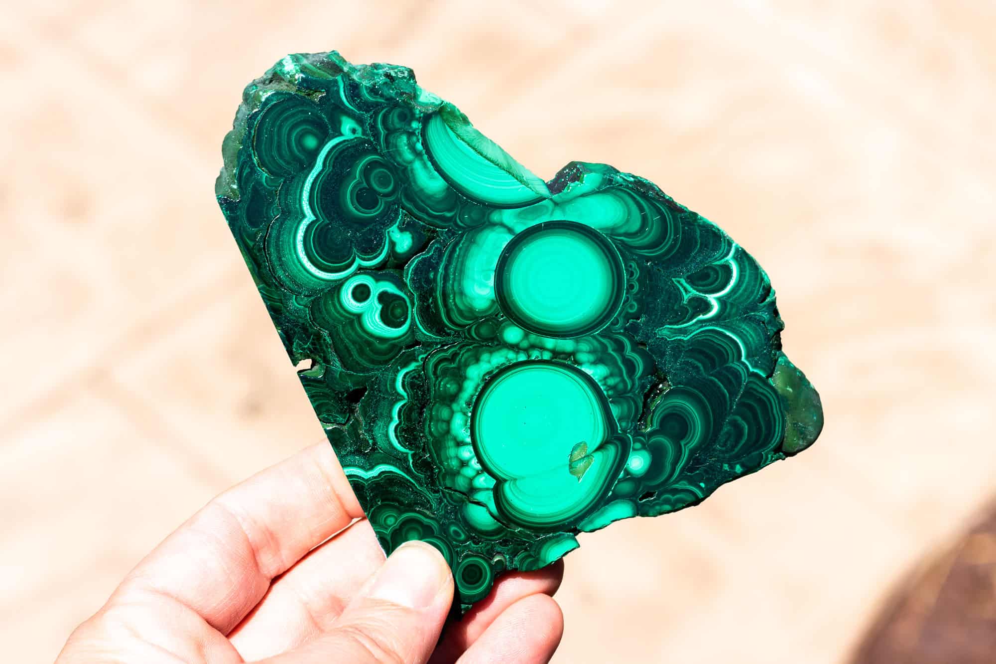 A hand holding up a malachite slab.