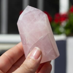 A rose quartz tower being held up.