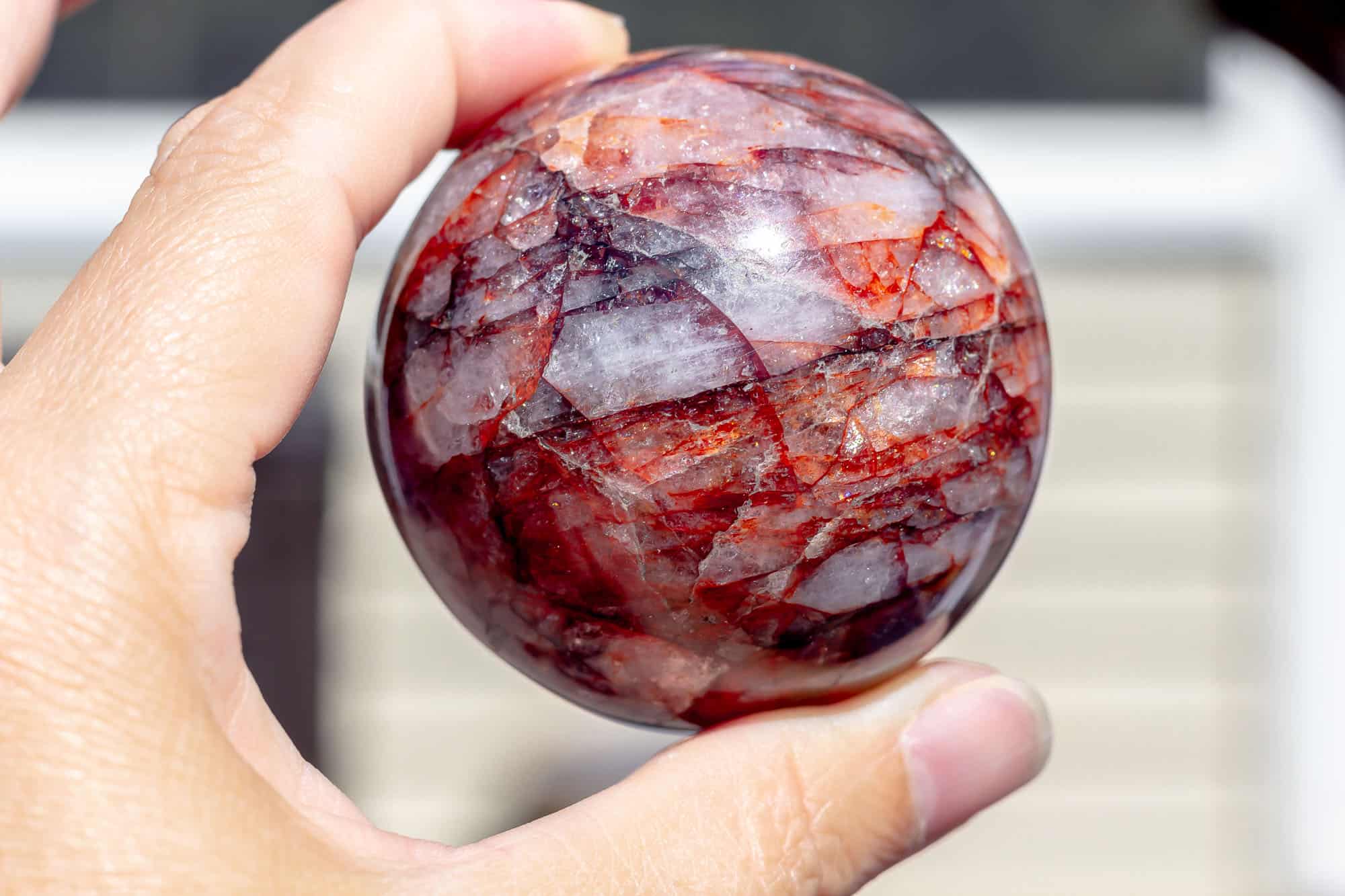 A red hematoid quartz sphere being held up.