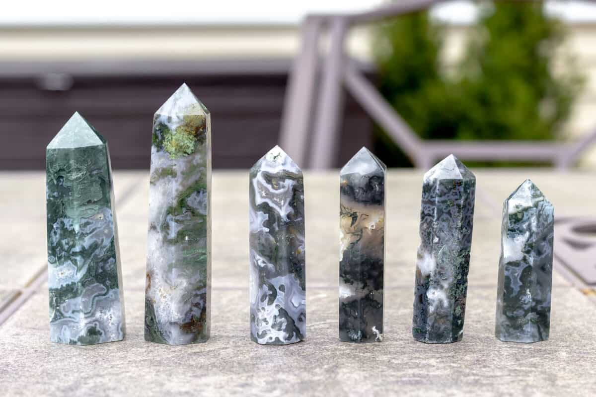 6 moss agate towers lined up on a table.