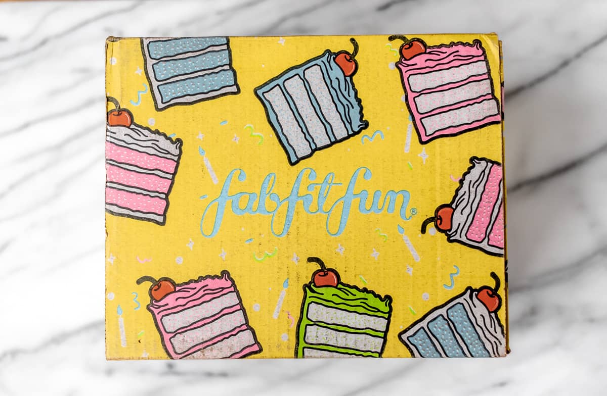A yellow FabFitFun box with pictures of cake on it.