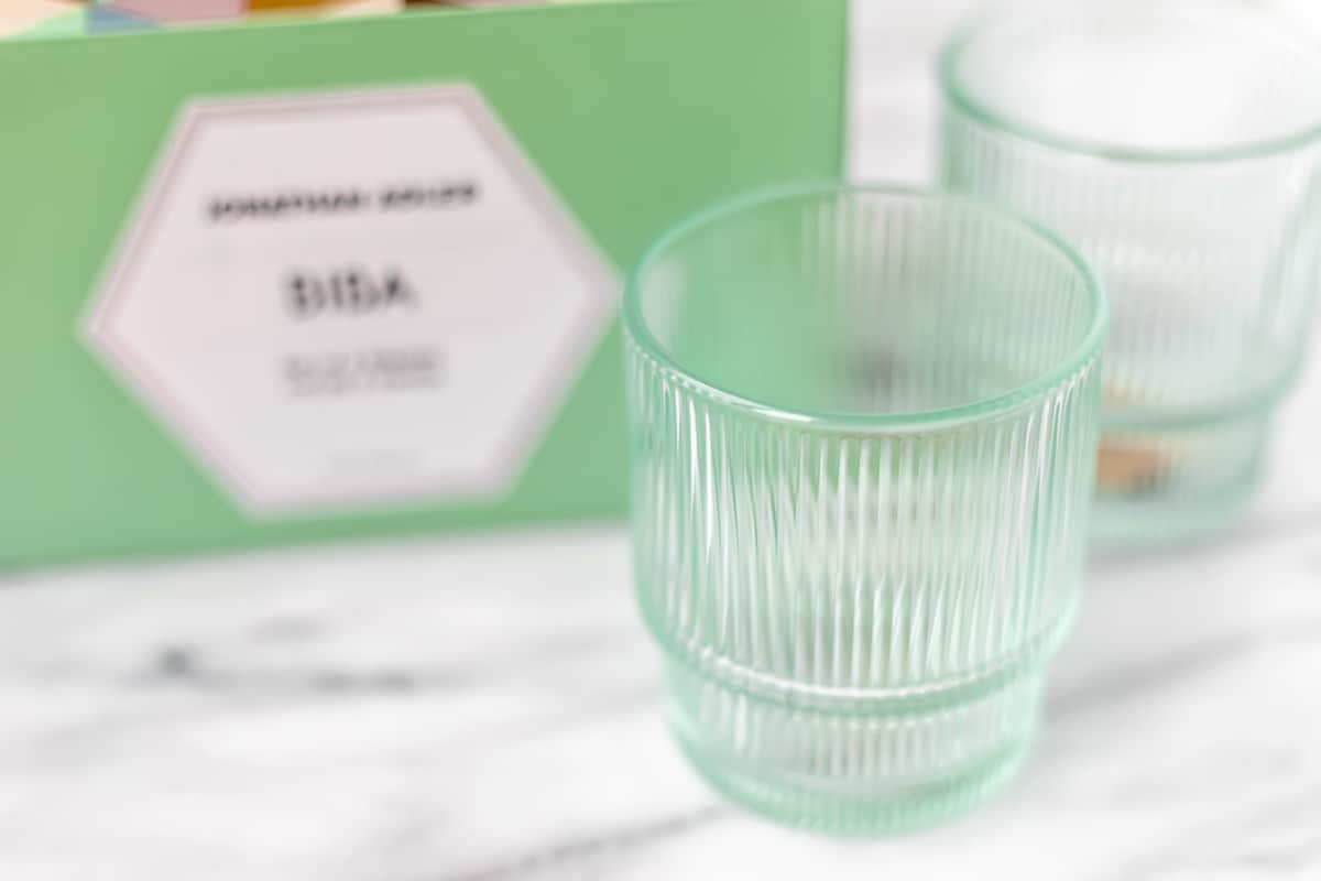 Ribbed green glasses with a Johnathan Adler box for them blurred in the background.