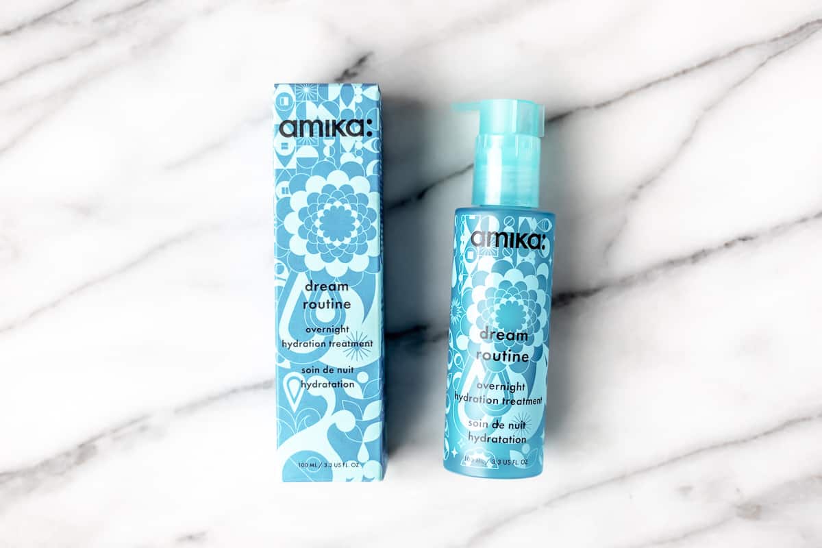 Amika overnight hydration treatment bottle and box on a marble background.