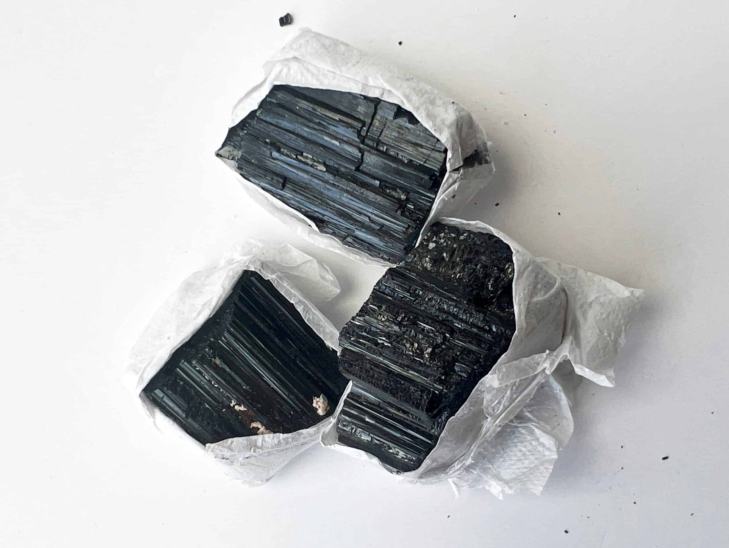 Three raw pieces of black tourmaline on a white background.