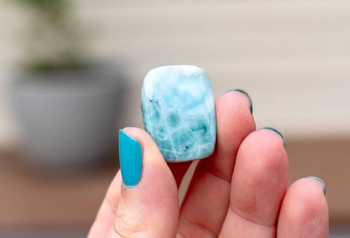 A square Larimar cabochon being held up.