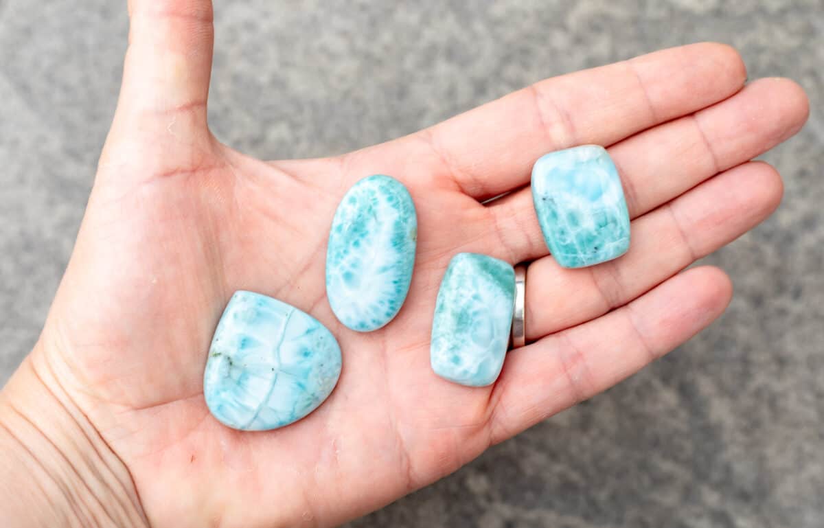 A hand out with 4 Larimar cabochons on it.