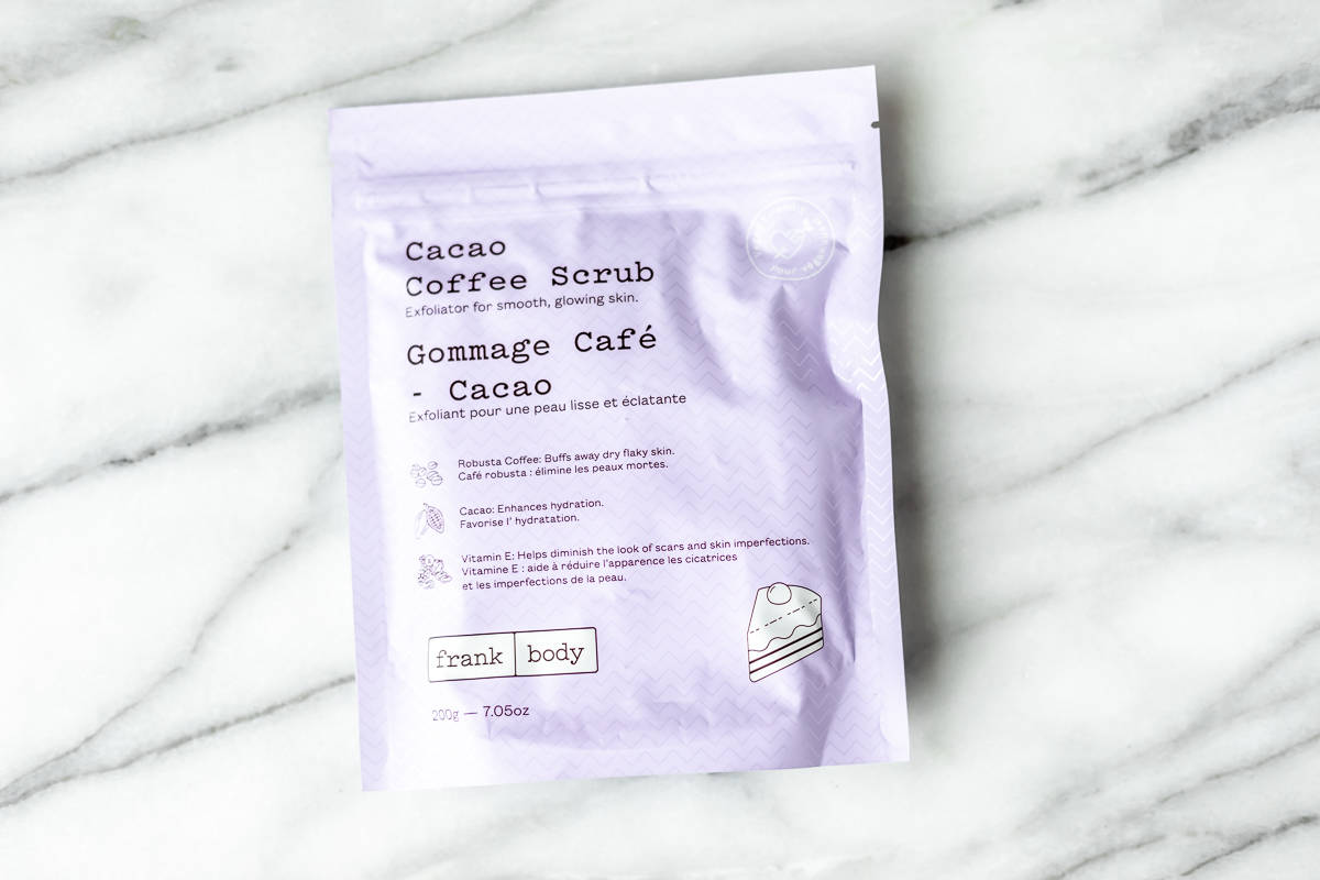 A purple pouch of Frank Body coffee scrub on a marble background.