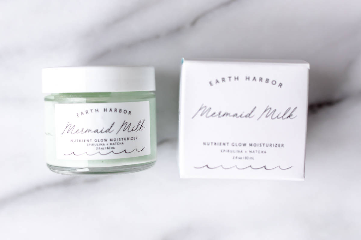 Mermaid Milk Moisturizer by Earth Harbor jar and box on a marble background.