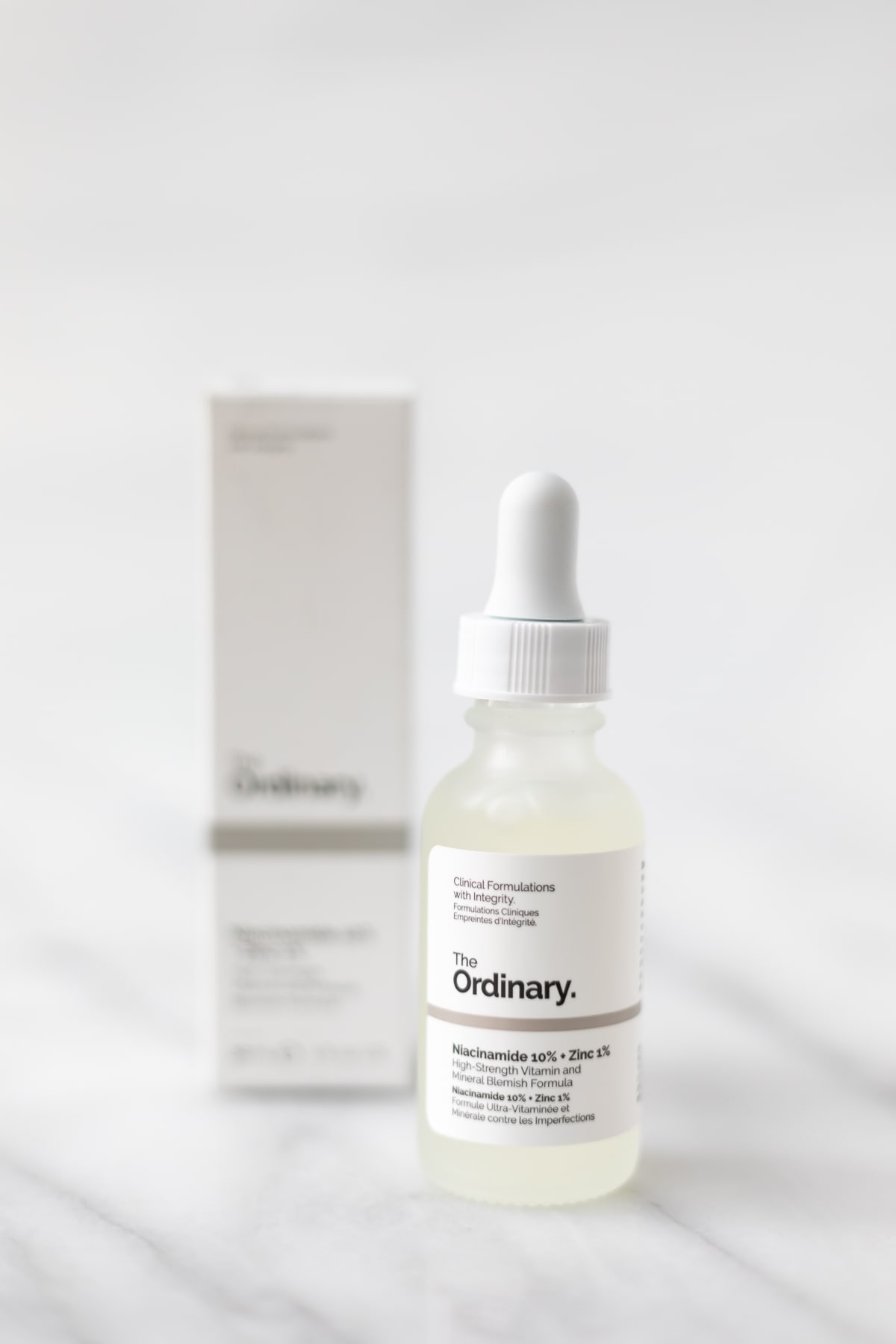 The Ordinary Niacinamide bottle and box on a marble table.
