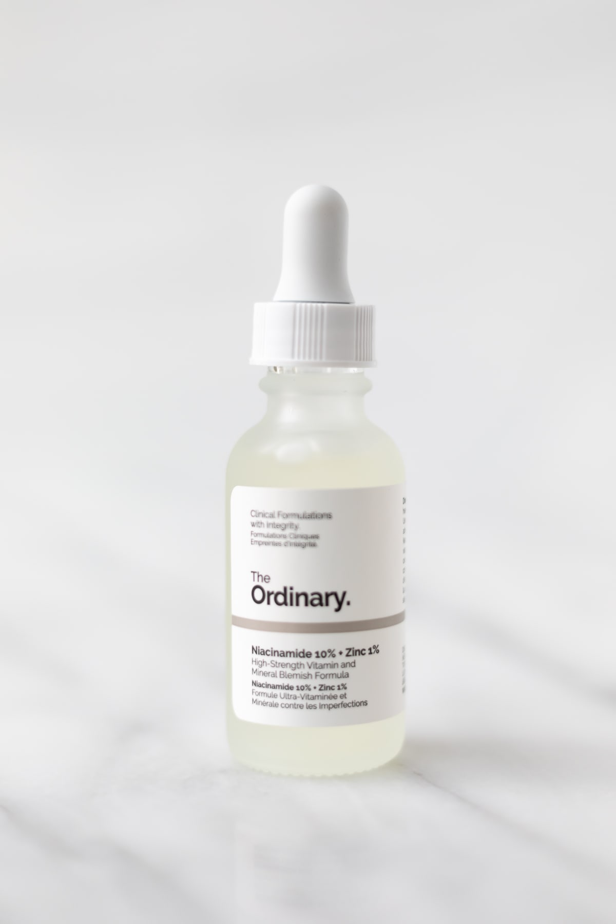 A bottle of The Ordinary Niacinamide 10% + Zinc 1% on a marble table.