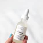 A hand holding a bottle of The ordinary Niacinamide with text overlay.