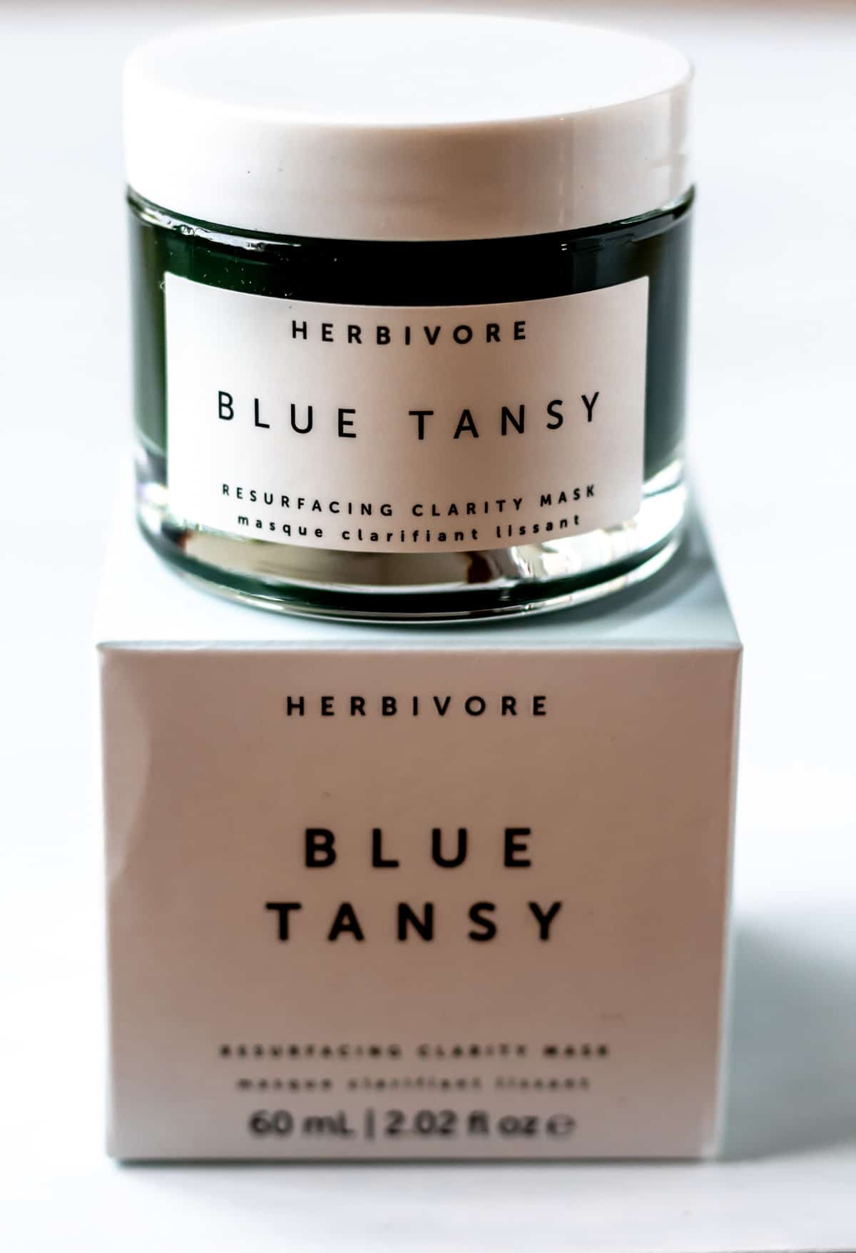 A jar of Herbivore Blue Tansy mask on top of the box that it comes in.