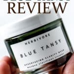 A hand holding up a jar of Herbivore Blue Tansy face mask with text overlay.