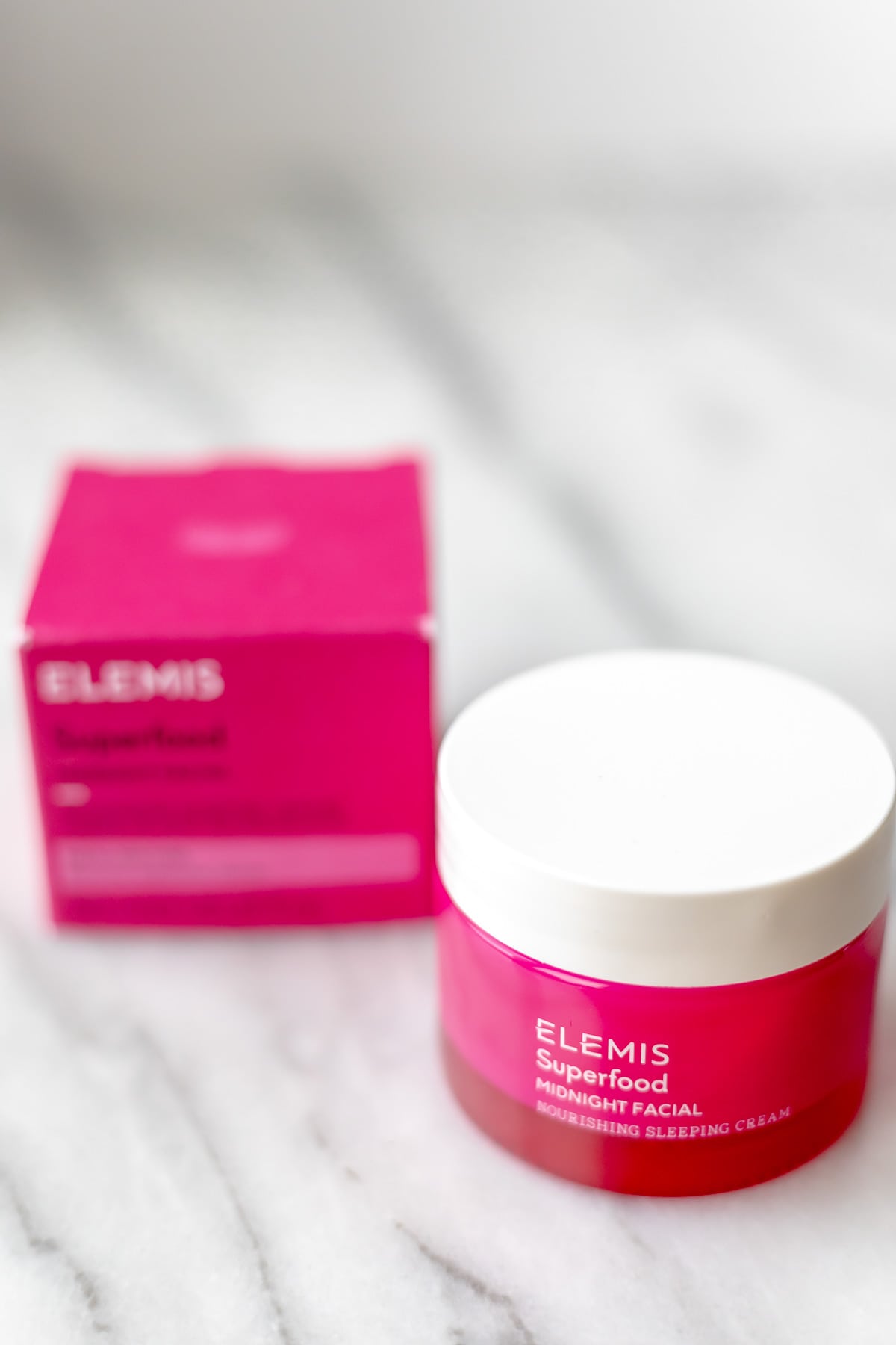 A jar of Elemis Midnight Facial and the box it comes in on a marble background.