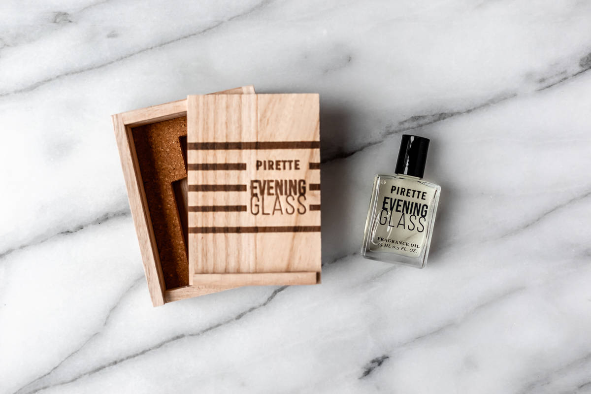 The Evening Glass Fragrance Oil by Pirette wood box and glass bottle on a marble background.