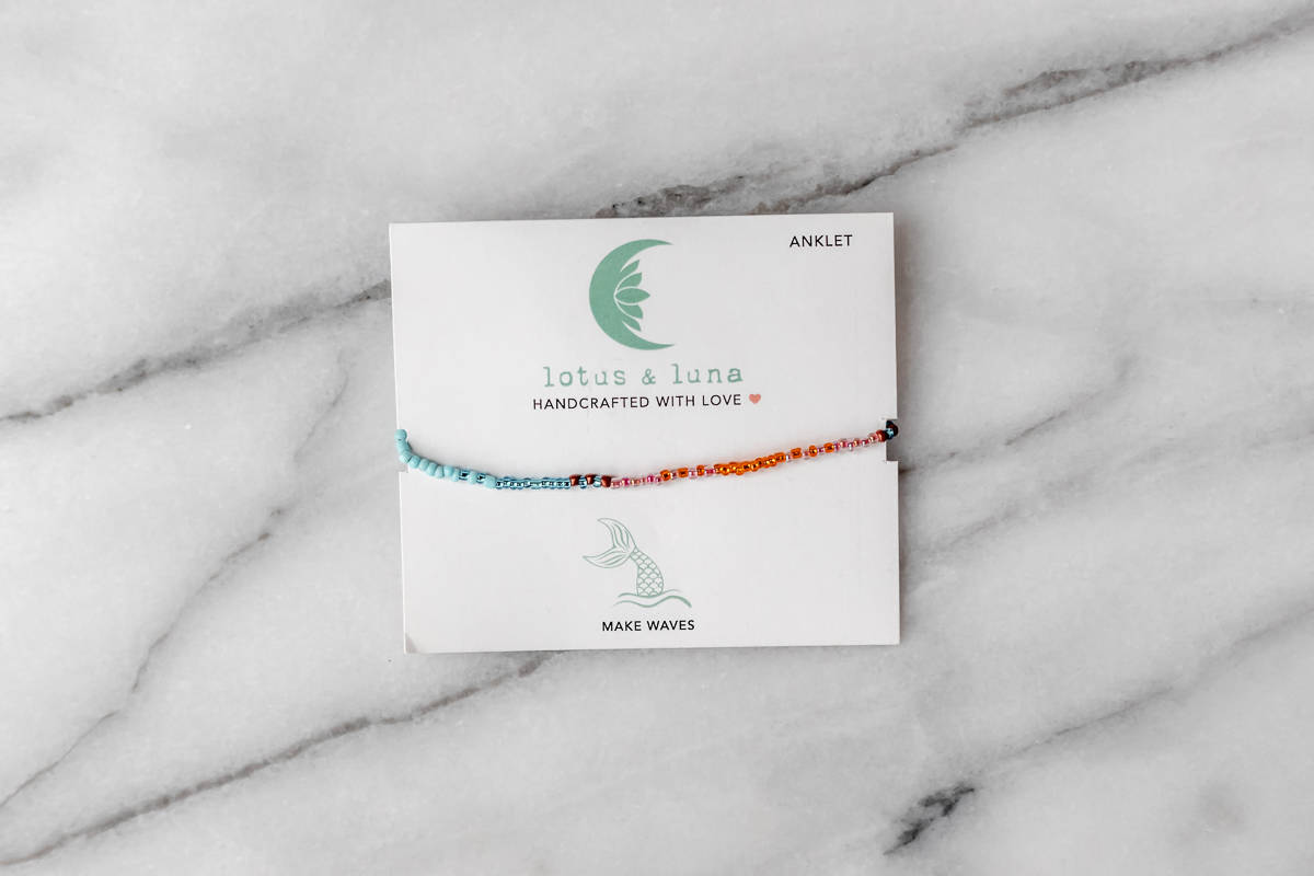 The Mermaid’s Tale Beaded Anklet by Lotus and Luna in it's packaging on a marble background.